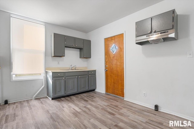 kitchen with gray cabinetry, sink, and light hardwood / wood-style flooring