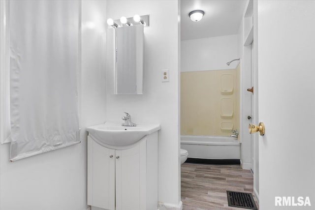 full bathroom with hardwood / wood-style flooring, vanity,  shower combination, and toilet