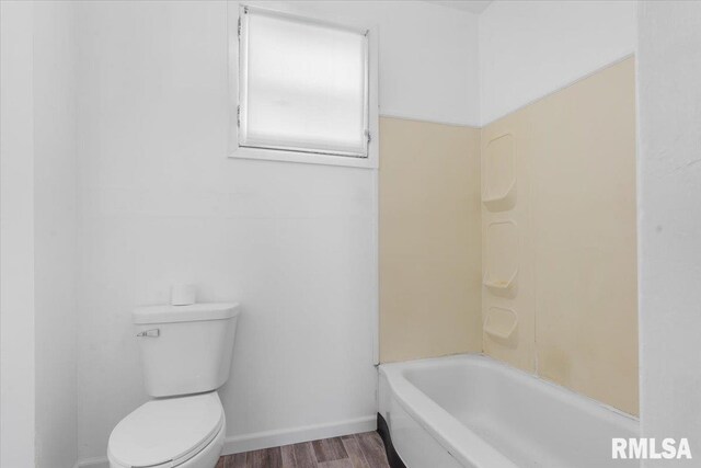 bathroom featuring hardwood / wood-style flooring, toilet, and a tub to relax in