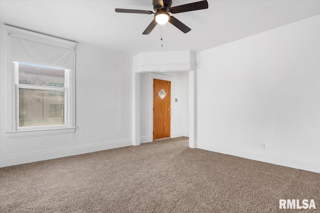 carpeted spare room featuring ceiling fan and baseboards