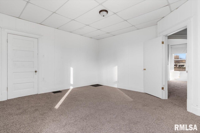 carpeted empty room featuring a paneled ceiling