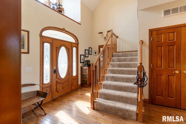 foyer entrance with high vaulted ceiling and light wood-type flooring