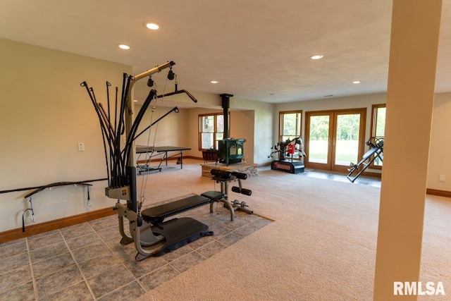 workout room with carpet, a wood stove, and french doors