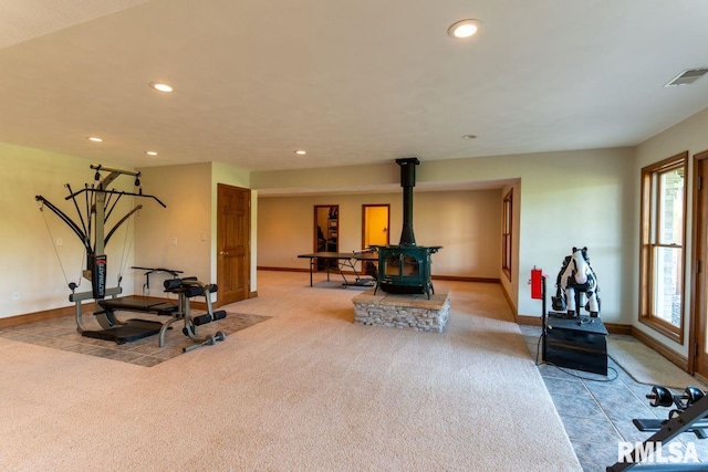 workout room with light colored carpet and a wood stove