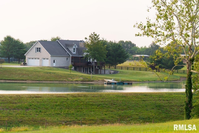 view of home's community with a lawn, a garage, and a deck with water view