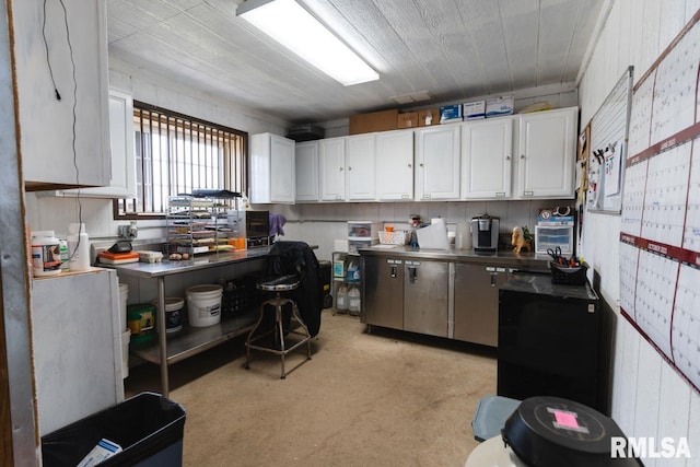 kitchen featuring light colored carpet, white cabinetry, and wooden walls