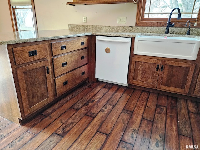 kitchen featuring white dishwasher, light stone counters, dark hardwood / wood-style floors, and sink