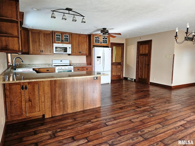 kitchen featuring sink, dark hardwood / wood-style flooring, kitchen peninsula, a textured ceiling, and white appliances