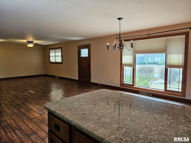 kitchen featuring pendant lighting, dark hardwood / wood-style floors, ceiling fan with notable chandelier, and a textured ceiling