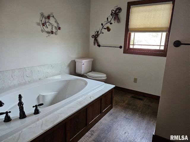 bathroom featuring hardwood / wood-style floors, a washtub, and toilet