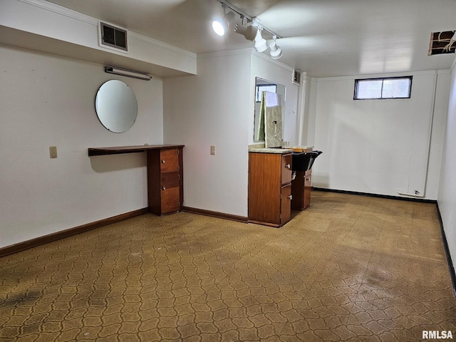 basement featuring ornamental molding and track lighting