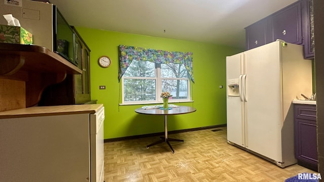 kitchen with light parquet flooring, butcher block countertops, and white fridge with ice dispenser