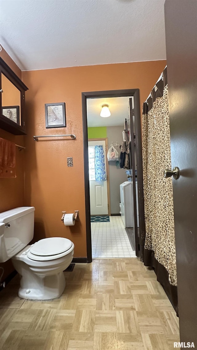 bathroom featuring toilet and washer / dryer