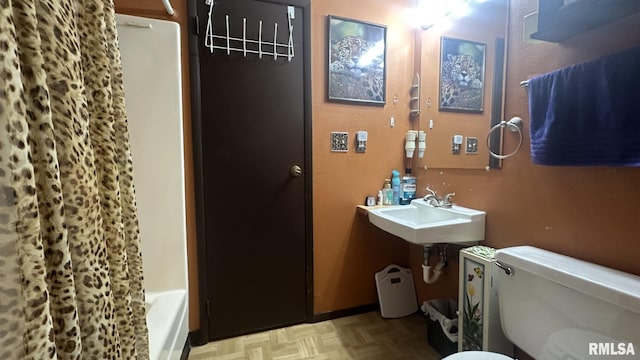 bathroom featuring toilet, parquet floors, and sink