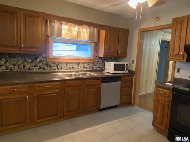 kitchen with sink, decorative backsplash, light tile patterned floors, black / electric stove, and dishwashing machine