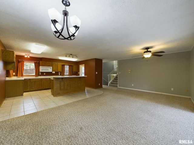 kitchen featuring ceiling fan with notable chandelier, light tile patterned floors, a textured ceiling, and decorative light fixtures