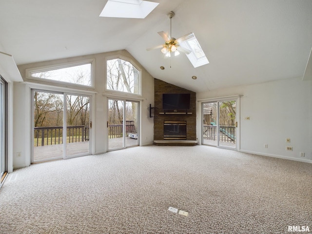 unfurnished living room featuring a skylight, ceiling fan, high vaulted ceiling, a fireplace, and carpet floors