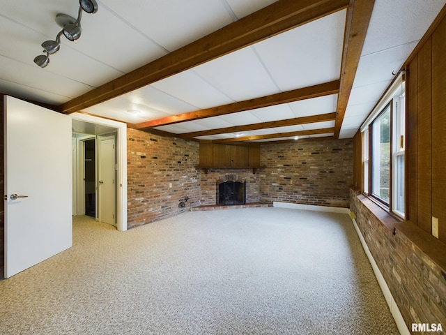 unfurnished living room featuring carpet flooring, beam ceiling, a brick fireplace, and brick wall