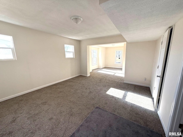 unfurnished room featuring carpet flooring, a textured ceiling, and a healthy amount of sunlight