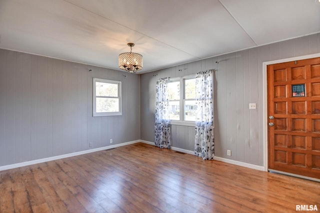 entrance foyer with hardwood / wood-style floors, a notable chandelier, and wood walls