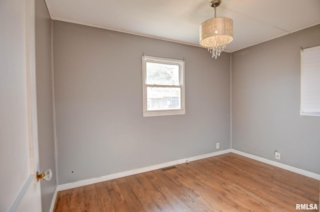 unfurnished room with a chandelier and hardwood / wood-style flooring