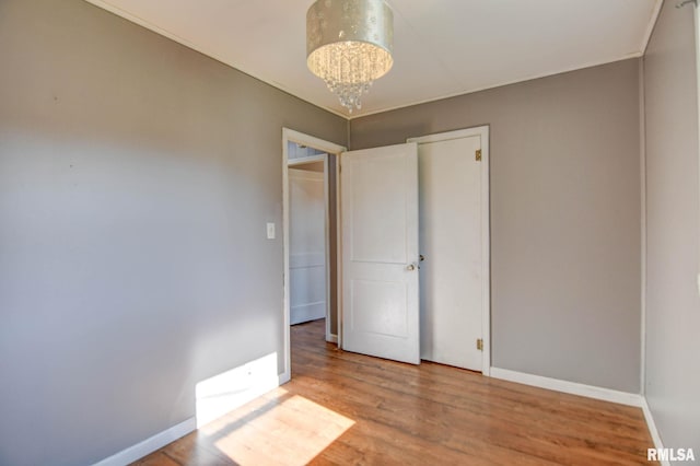 unfurnished bedroom with wood-type flooring and a notable chandelier