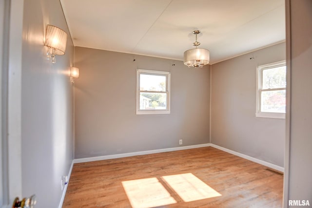 unfurnished room with light hardwood / wood-style floors and a notable chandelier