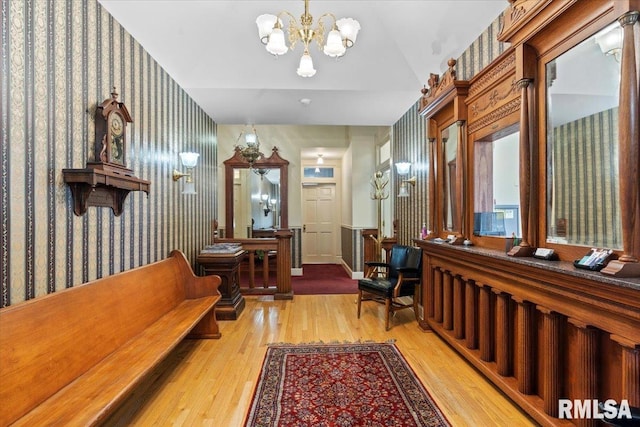 hall featuring light wood-type flooring and an inviting chandelier