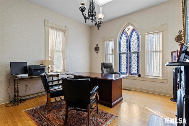 home office with a chandelier and light hardwood / wood-style flooring