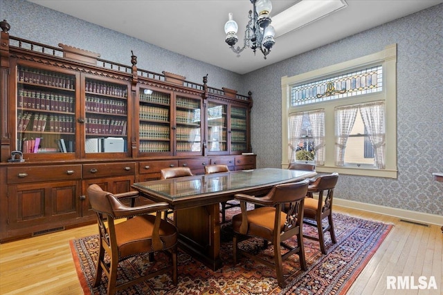 dining area with light hardwood / wood-style floors and a chandelier