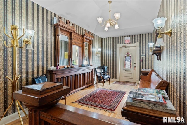 living area featuring hardwood / wood-style floors, lofted ceiling, and an inviting chandelier