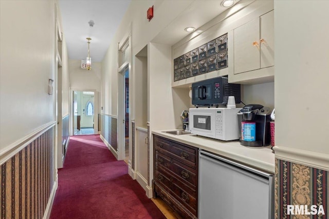 kitchen with decorative light fixtures, carpet floors, and sink