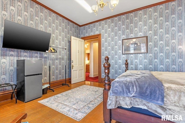 bedroom featuring a chandelier, stainless steel fridge, hardwood / wood-style flooring, and ornamental molding