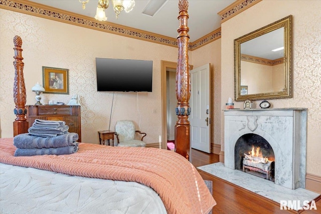 bedroom with crown molding, a fireplace, and wood-type flooring