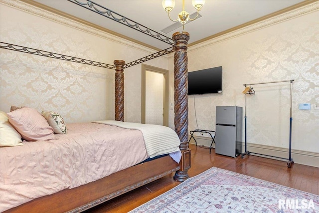 bedroom with stainless steel fridge, hardwood / wood-style floors, an inviting chandelier, and ornamental molding