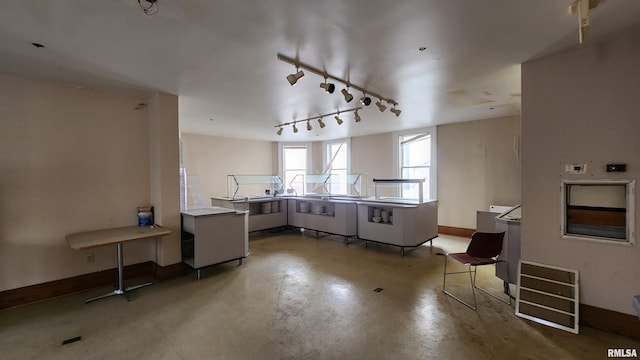 kitchen with track lighting, concrete floors, and kitchen peninsula