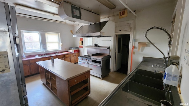 kitchen with ventilation hood, sink, a kitchen island, and stainless steel fridge