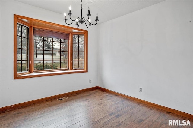 unfurnished dining area featuring wood-type flooring and an inviting chandelier