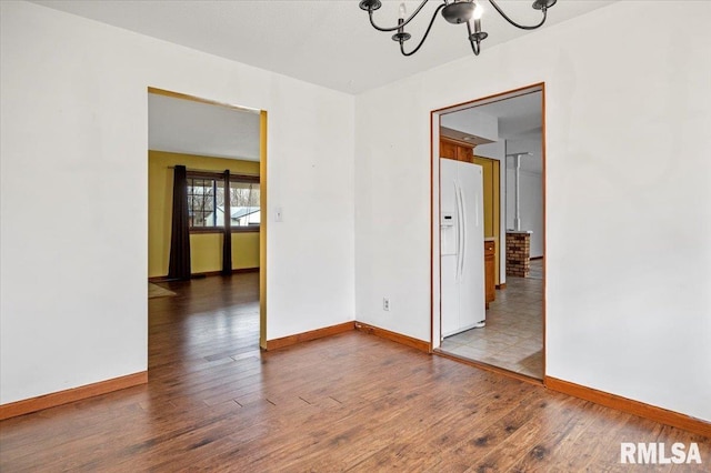 unfurnished room featuring a notable chandelier and wood-type flooring