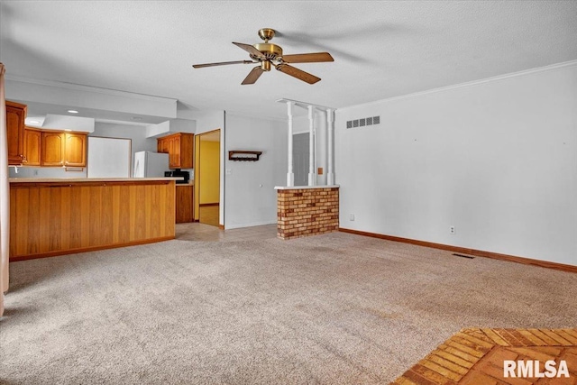 unfurnished living room featuring ceiling fan, light colored carpet, ornamental molding, and a textured ceiling