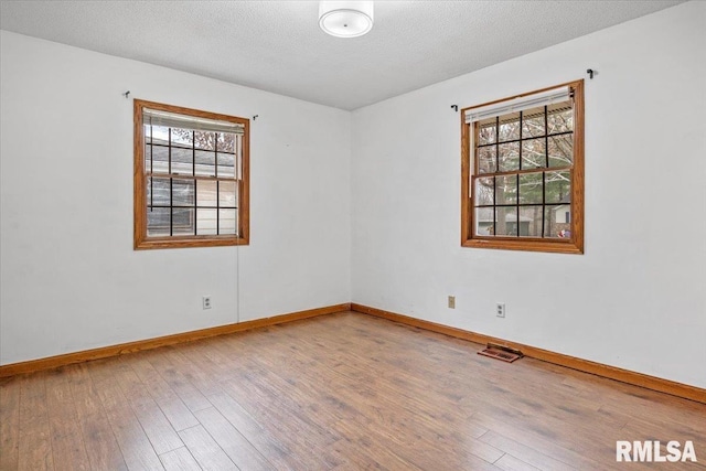 spare room with a textured ceiling, hardwood / wood-style flooring, and plenty of natural light