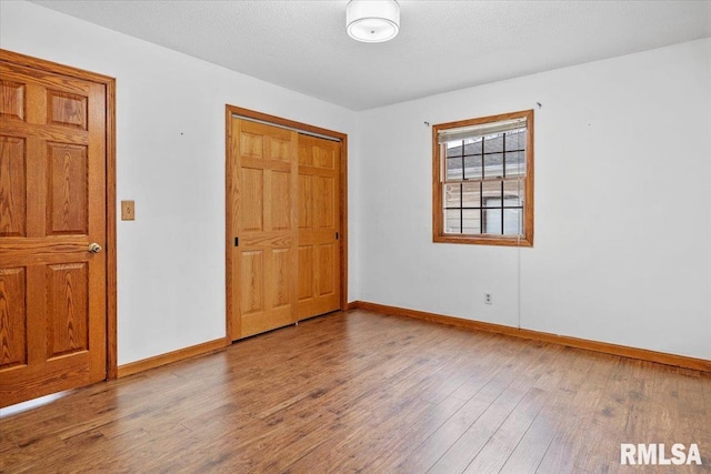 unfurnished bedroom featuring a closet, a textured ceiling, and hardwood / wood-style flooring