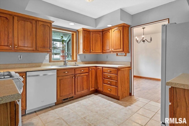 kitchen featuring sink, stainless steel appliances, a chandelier, decorative light fixtures, and light tile patterned floors