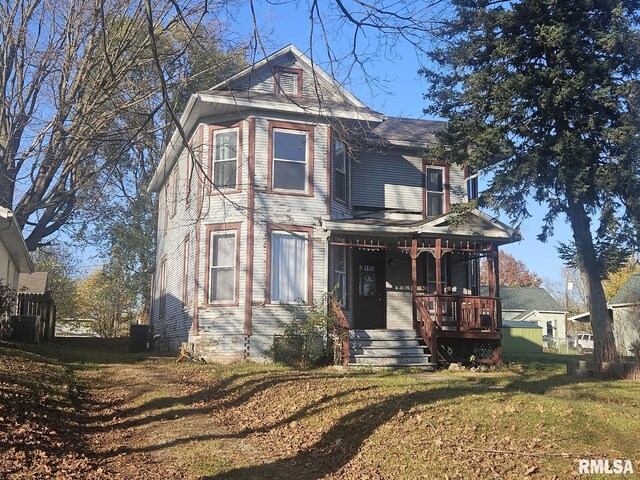 view of front of property featuring a front yard, a porch, and cooling unit