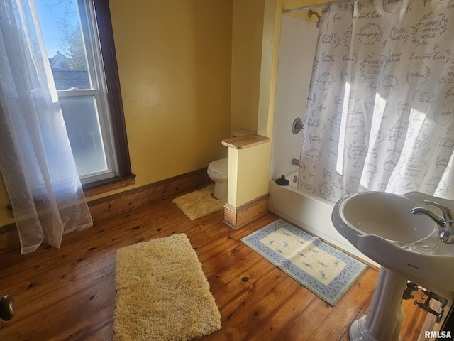 bathroom featuring hardwood / wood-style flooring, shower / bath combination with curtain, and toilet