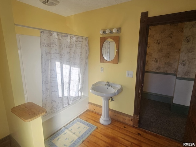 bathroom featuring wood-type flooring and a textured ceiling