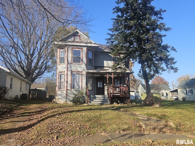 victorian house with a porch, central AC, and a front lawn