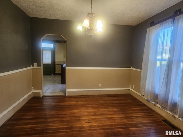 unfurnished room featuring dark hardwood / wood-style flooring, a textured ceiling, and a chandelier