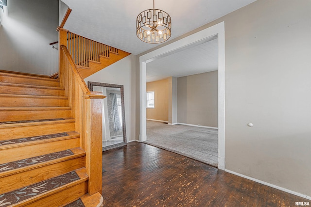 stairs featuring hardwood / wood-style floors and an inviting chandelier