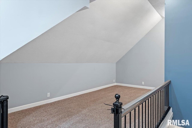 additional living space featuring vaulted ceiling and carpet flooring